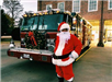 Person in Santa Costume in Front of Decorated Fire Truck