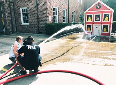 Firefighter Helping Kid Use Fire Hose